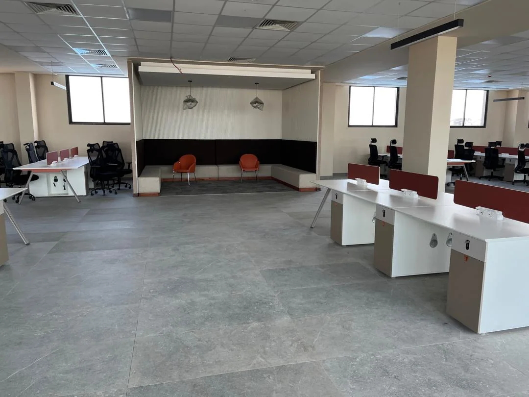 Open plan workstations beside a breakout lounge with orange accent chairs